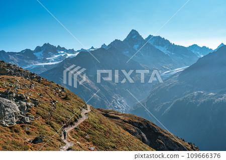 Woman with backpack hiking with Mont Blanc massif in French Alps on trail of Lac Blanc at France 109666376