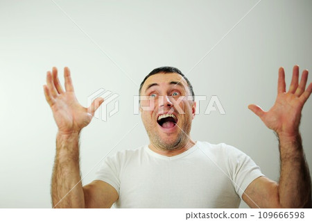 Win fun vacation travelDifferent cheerful positive emotions of an adult man with gray black hair Open funny cheerful blue eyes White t-shirt gray background wrinkle forehead stick out tongue Win fun vacation travelDifferent cheerful positive emotions of an adult man with gray black hair Open funny cheerful blue eyes White t-shirt gray background wrinkle forehead stick out tongue 109666598