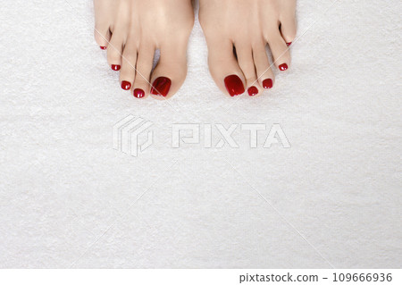 Female toes with glossy red pedicure on white terry towel, copy space. Female toes with glossy red pedicure on white terry towel, copy space. 109666936