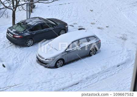 One of the cars in the parking lot is covered with snow, view from above. 109667582