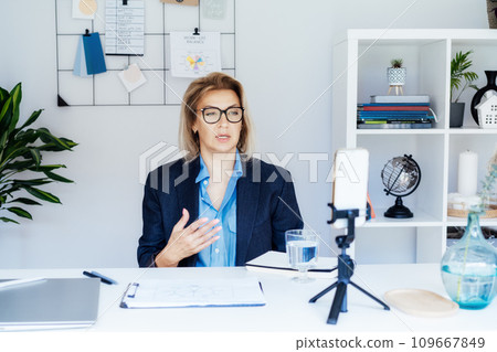 50's confident mature businesswoman, middle-aged experienced senior female professional recording video vlog webinar, online course. Female edtech entrepreneur shares skills, blogger online business 50's confident mature businesswoman, middle-aged experienced senior female professional recording video vlog webinar, online course. Female edtech entrepreneur shares skills, blogger online business 109667849