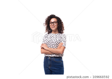 a slender young stylish woman with a curly haircut dressed in a blouse with polka dots wears glasses 109668592