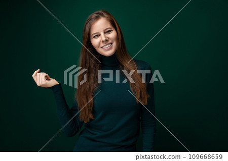 Charming young woman with long brown hair on dark green background Charming young woman with long brown hair on dark green background 109668659