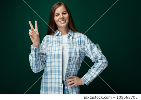 Cheerful woman dressed in a white turtleneck and shirt shows a hello gesture Cheerful woman dressed in a white turtleneck and shirt shows a hello gesture 109668705