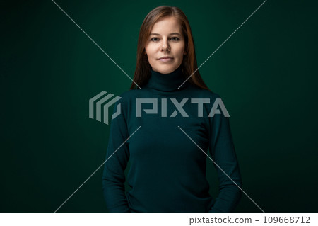 Portrait of a well-groomed young woman with brown eyes on a dark green background Portrait of a well-groomed young woman with brown eyes on a dark green background 109668712