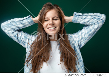 Beautiful European woman in a shirt and jeans posing at the camera on a green studio background Beautiful European woman in a shirt and jeans posing at the camera on a green studio background 109668735