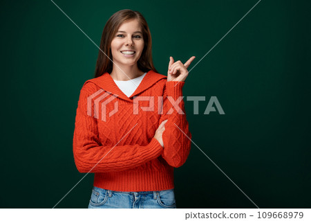 Joyful lucky woman wearing a red sweater on a dark green background Joyful lucky woman wearing a red sweater on a dark green background 109668979