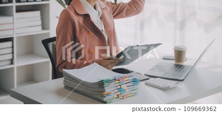 Portrait of Young Asian woman hand freelancer is working her job on computer tablet in modern office. Doing accounting analysis report real estate investment data, Financial and tax systems concept. Portrait of Young Asian woman hand freelancer is working her job on computer tablet in modern office. Doing accounting analysis report real estate investment data, Financial and tax systems concept. 109669362
