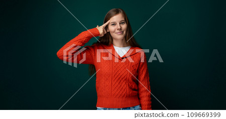 Attractive young woman dressed in a red sweater smiling on a green background 109669399