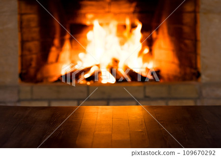 Empty old wooden table against burning wood in the fireplace 109670292