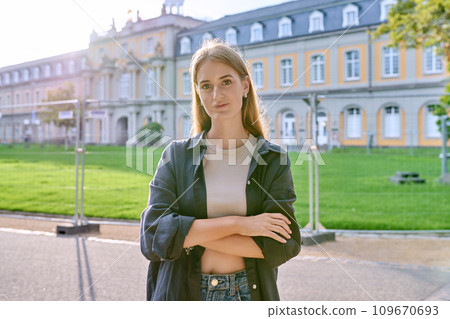 Young girl student posing outdoors, background of educational building Young girl student posing outdoors, background of educational building 109670693