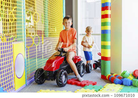 A child rides a toy pedal car at a children's play center 109671010