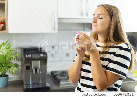 Attractive woman enjoying freshly made coffee in the kitchen in the morning 109671831