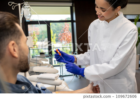 Nurse or doctor making vitamin IV infusion drip for male patient in hospital or beauty salon. Nurse or doctor making vitamin IV infusion drip for male patient in hospital or beauty salon. 109672606
