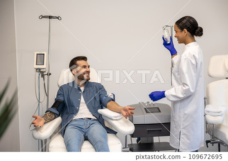 Smiling man doing insertion of drip in clinic. 109672695