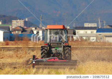 Tractor plowing a rice field in the countryside 109673512
