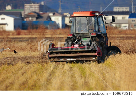 Tractor plowing a rice field in the countryside 109673515
