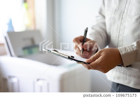 一名身穿灰色工作服的承包商正在檢查洗衣機。 一名身穿灰色工作服的承包商正在檢查洗衣機。 109675173