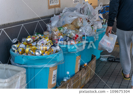 Overflowing garbage collection site, man throwing away garbage 109675304