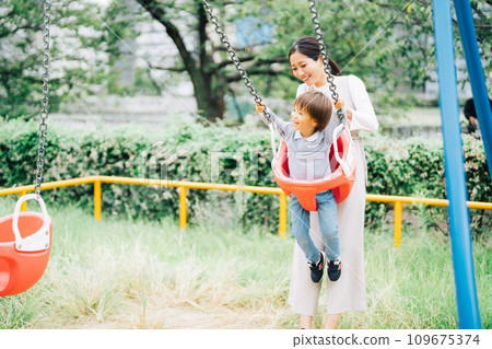 Parent and child swinging in the park 109675374