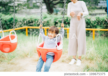 Parent and child swinging in the park 109675375
