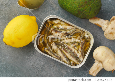 open tin of sardines on white tiles background. open tin of sardines on white tiles background. 109676428
