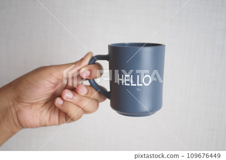 hand holding a blue coffee cup with hello word hand holding a blue coffee cup with hello word 109676449