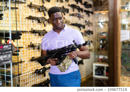 Portrait of african american man in gun shop showing rifle Portrait of african american man in gun shop showing rifle 109677519