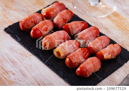Miniature sausage links wrapped in bacon Miniature sausage links wrapped in bacon 109677529