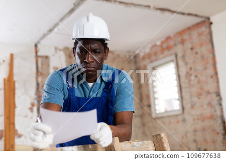 Frustrated african american foreman standing with papers at construction site 109677638