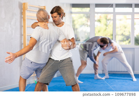 Man and senior man athletes in pair conduct training battle in oriental fighting technique 109677898