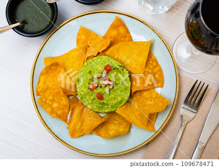 Corn chips with guacamole sauce. Corn chips with guacamole sauce. 109678471