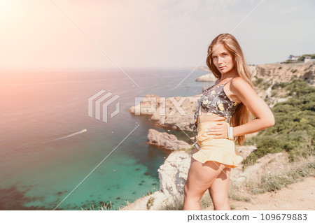 Woman travel sea. Happy tourist enjoy taking picture outdoors for memories. Woman traveler looks at the edge of the cliff on the sea bay of mountains, sharing travel adventure journey Woman travel sea. Happy tourist enjoy taking picture outdoors for memories. Woman traveler looks at the edge of the cliff on the sea bay of mountains, sharing travel adventure journey 109679883