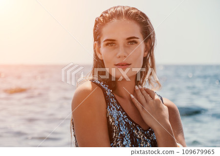 Woman summer travel sea. Happy tourist enjoy taking picture outdoors for memories. Woman traveler posing on the beach at sea surrounded by volcanic mountains, sharing travel adventure journey 109679965