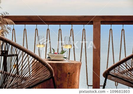 Close front view of two glasses of wine on a wooden table. In the background is the sea and the sky. Copy Space. 109681803