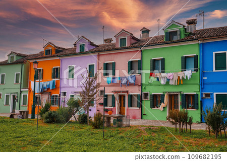 Colorful row of houses in Burano, Italy. No boats or bridges visible. Quiet atmosphere with no activity. Unique architecture and vibrant colors. 109682195