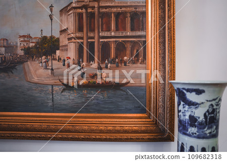 Blue and white vase next to a painting with predominant blue and white colors. Part of a collection featuring Venetian style interiors and popular places in Venice, Italy. 109682318
