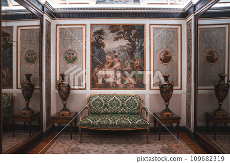 Luxurious and elegant room with green and white couch and ornate paintings on the wall. Opulent decor exudes sophistication. Part of a collection of Venice photos in real Venetian style. 109682319