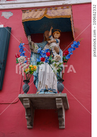 Explore the charm of Venice, Italy with this image of a statue on the side of a vibrant red building. Discover the beauty of Venetian architecture and historical landmarks. 109682332