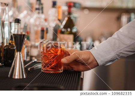 Bartender pouring vibrant red drink into martini glass, showcasing elegance and precision of mixology. Part of Venice collection, suggesting luxury and sophistication in the city's dining scene. Bartender pouring vibrant red drink into martini glass, showcasing elegance and precision of mixology. Part of Venice collection, suggesting luxury and sophistication in the city's dining scene. 109682335