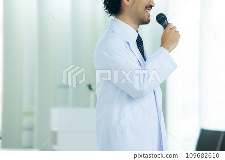 A man in a white coat speaking at a seminar A man in a white coat speaking at a seminar 109682610