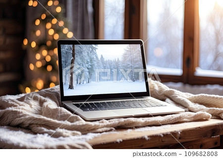 Laptop with a winter landscape screen, indoor on the table with a cozy blanket by the window with snow. Seasonal remote work, internet, shopping, Christmas and New Year. AI generated Laptop with a winter landscape screen, indoor on the table with a cozy blanket by the window with snow. Seasonal remote work, internet, shopping, Christmas and New Year. AI generated 109682808