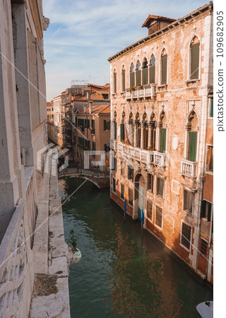 Explore the serene and picturesque canals of Venice, Italy with this calming view of a canal. The tranquil brown and green hues create a peaceful atmosphere. 109682905