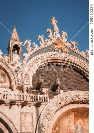 Aerial view of a Renaissance-style ornate building with vibrant colors and intricate details against a blue sky. Located in a city, possibly Venice, Italy. 109683220