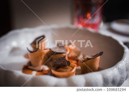 Table setting with white plate, food, red wine, and bread in warm indoor ambiance in Venice, Italy. Captures essence of leisurely dining experience. Table setting with white plate, food, red wine, and bread in warm indoor ambiance in Venice, Italy. Captures essence of leisurely dining experience. 109683294