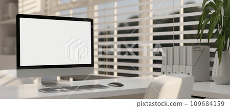 Modern white office with a computer white-screen mockup and office supplies on a white table. 109684159