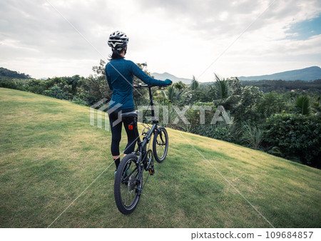 Riding folding bike to tropical mountain peak 109684857