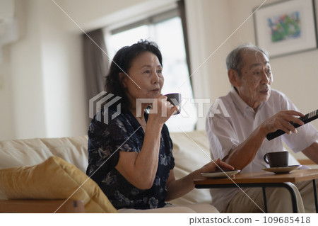 Daily life of a senior couple drinking coffee while watching TV 109685418