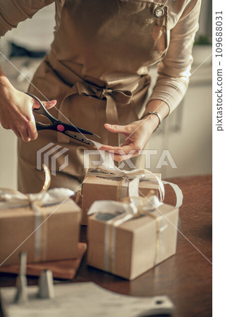 woman bakery shop owner cuts the ribbon on box for customer order. Bakery chef baking pastry and cake in the kitchen. Small business entrepreneur and food delivery concept. 109688031