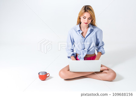 young woman sitting on the floor and using laptop 109688156